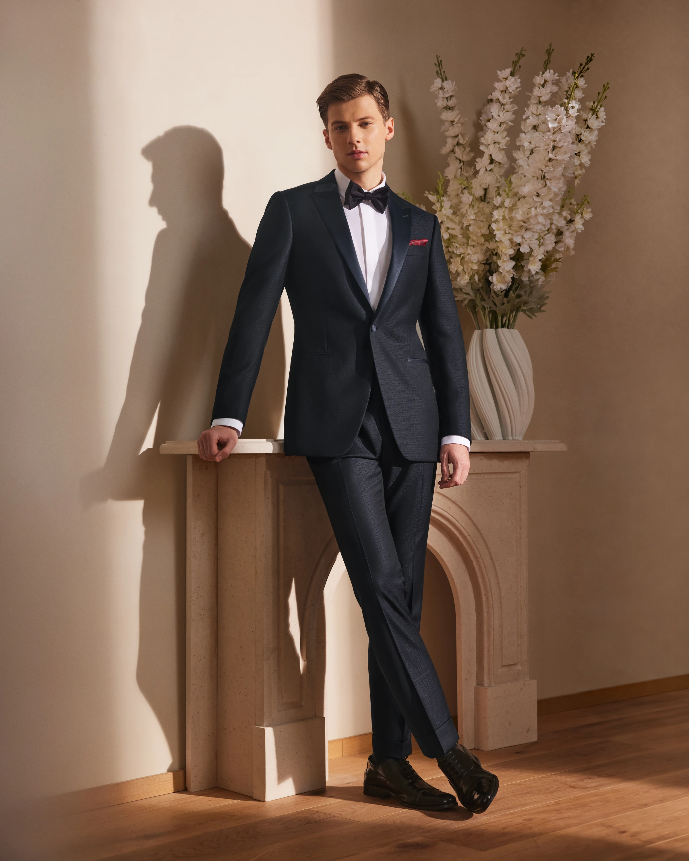 A groom walking naturally in a fitted navy wedding suit